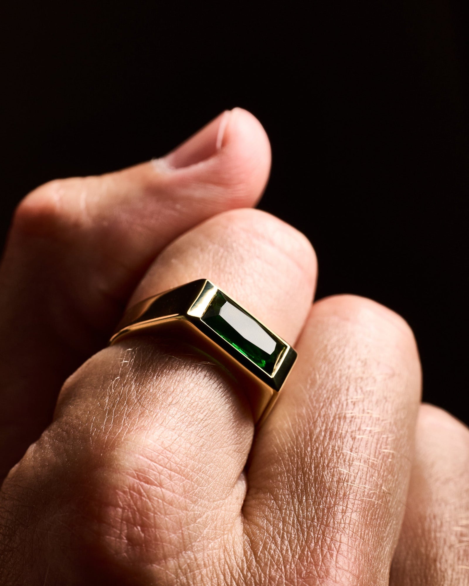 Gold Sona emerald ring worn on a model's hand